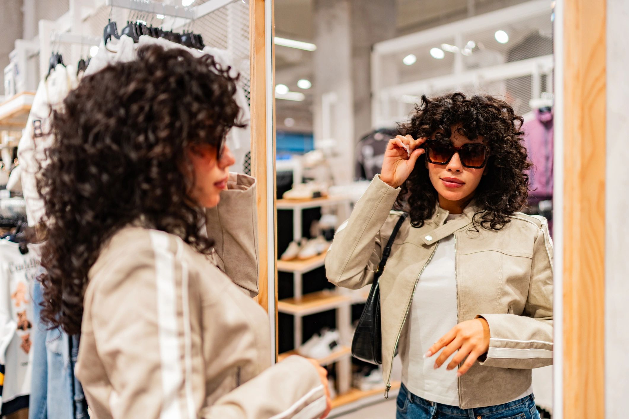 Customer trying on accessories in a store mirror, representing fit and styling